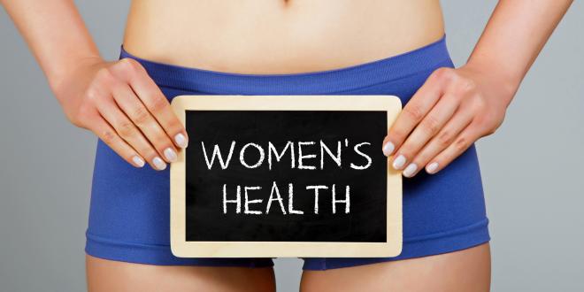 Woman in shorts holding a small blackboard that reads Women's Health.